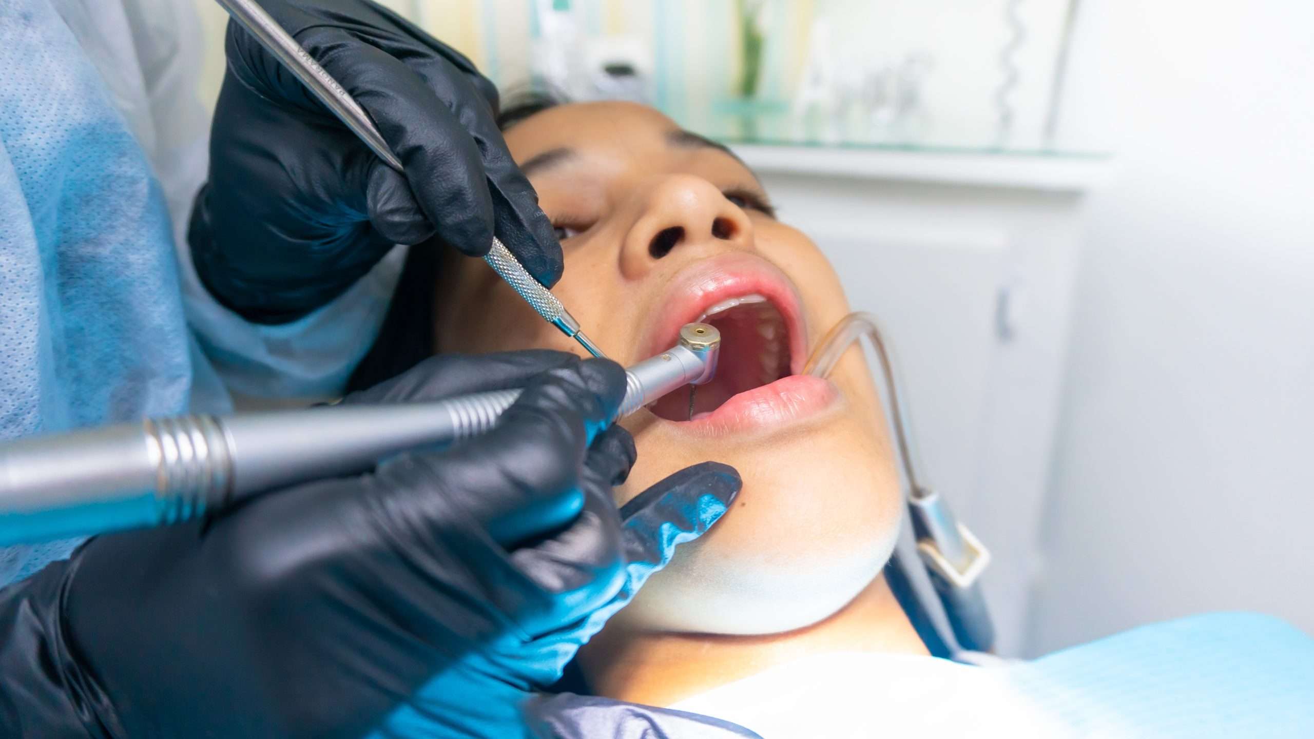 women at the dentist getting her teeth cleaning her teeth